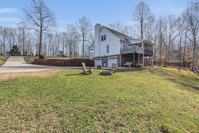 view of home's exterior with a fire pit, a yard, a chimney, and an attached garage