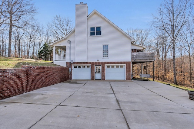 view of home's exterior featuring brick siding, a chimney, concrete driveway, a balcony, and a garage