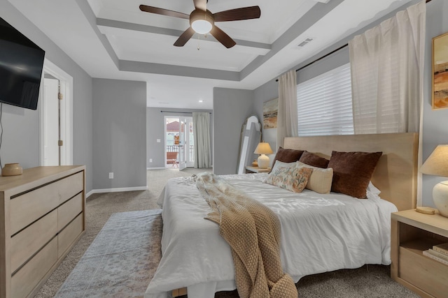 bedroom featuring ceiling fan, light carpet, visible vents, baseboards, and a tray ceiling