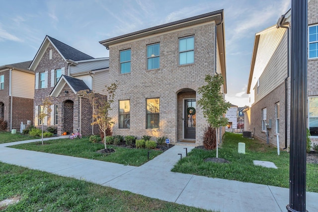 view of front of property with central AC, brick siding, and a front lawn