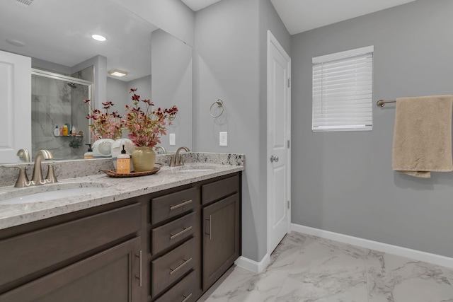 full bath featuring a sink, baseboards, marble finish floor, a shower stall, and double vanity