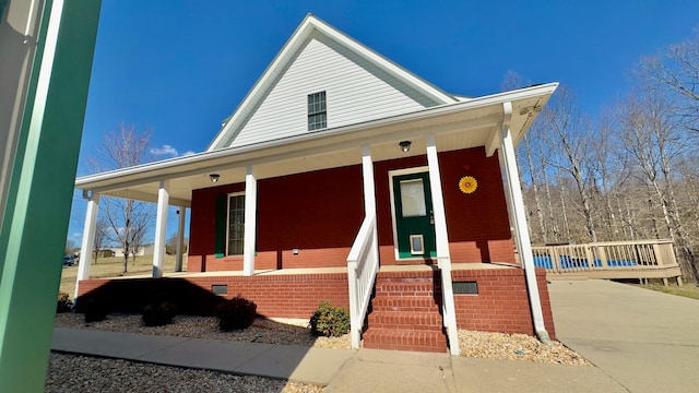 farmhouse inspired home with a porch, brick siding, driveway, and crawl space