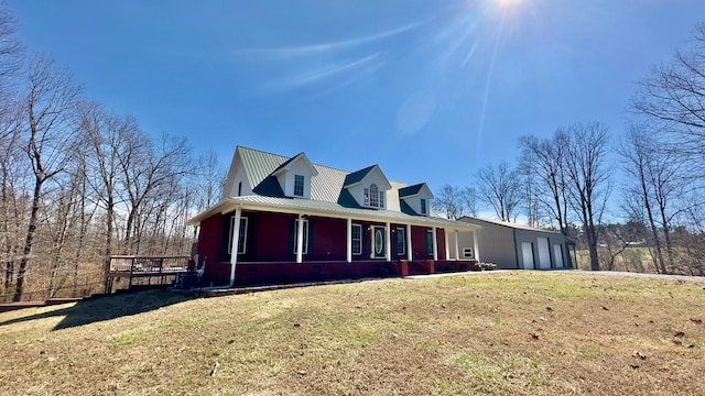 view of property exterior featuring an attached garage, a lawn, covered porch, and metal roof