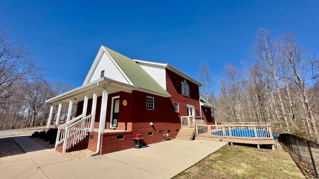 view of property exterior with crawl space, brick siding, metal roof, and fence