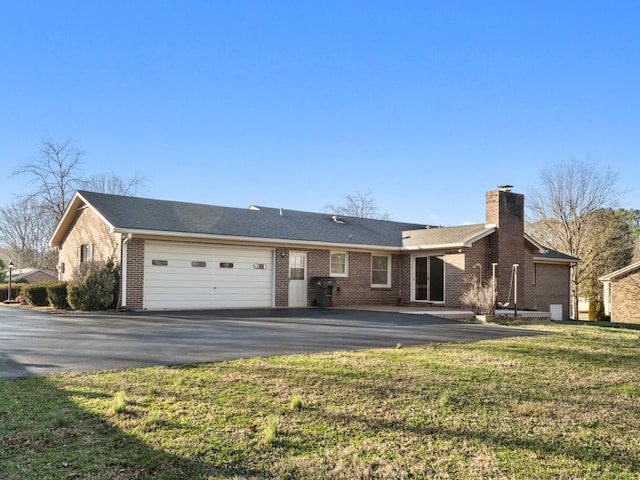 rear view of property featuring a garage, driveway, a lawn, a chimney, and brick siding