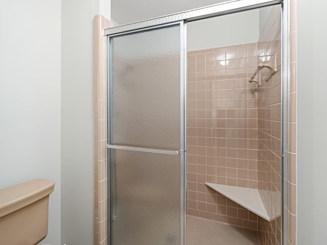 bathroom with toilet and a tile shower