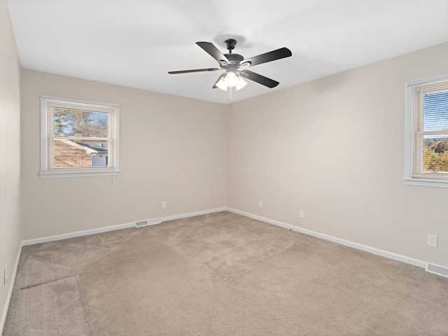 spare room featuring baseboards, visible vents, and light colored carpet