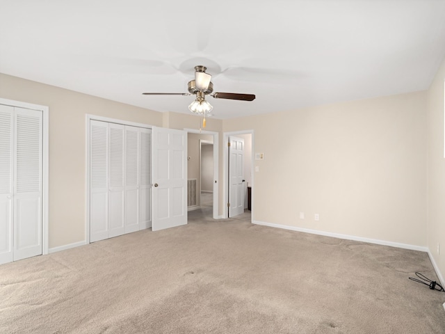 unfurnished bedroom with multiple closets, visible vents, a ceiling fan, light carpet, and baseboards