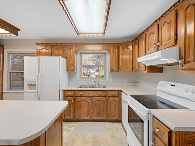 kitchen with light countertops, white appliances, brown cabinetry, and under cabinet range hood