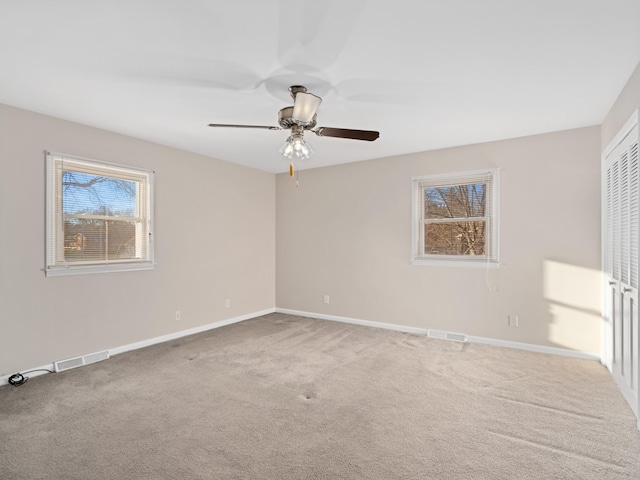 empty room with carpet, visible vents, and baseboards