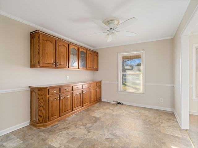 kitchen with brown cabinetry, ornamental molding, glass insert cabinets, a ceiling fan, and baseboards