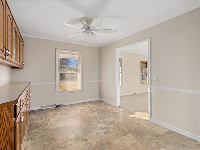 unfurnished dining area featuring visible vents, crown molding, baseboards, and a ceiling fan