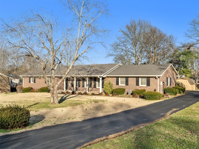 single story home featuring aphalt driveway, a front yard, and brick siding