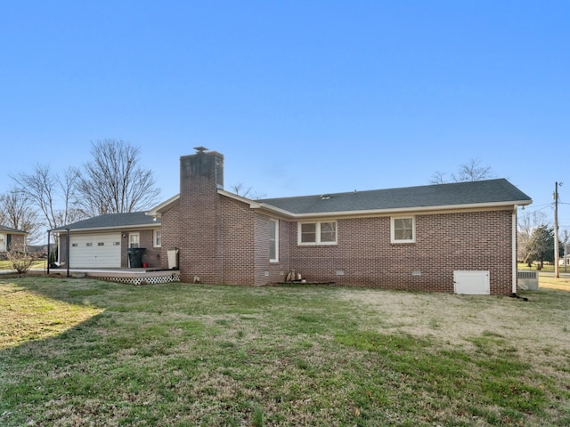 rear view of property with brick siding, a yard, a chimney, an attached garage, and crawl space