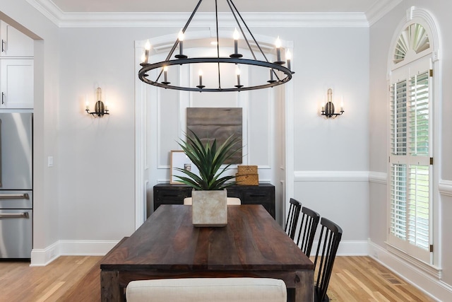 dining room with baseboards, light wood finished floors, an inviting chandelier, and crown molding