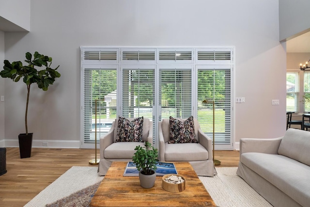 living area featuring an inviting chandelier, baseboards, and wood finished floors