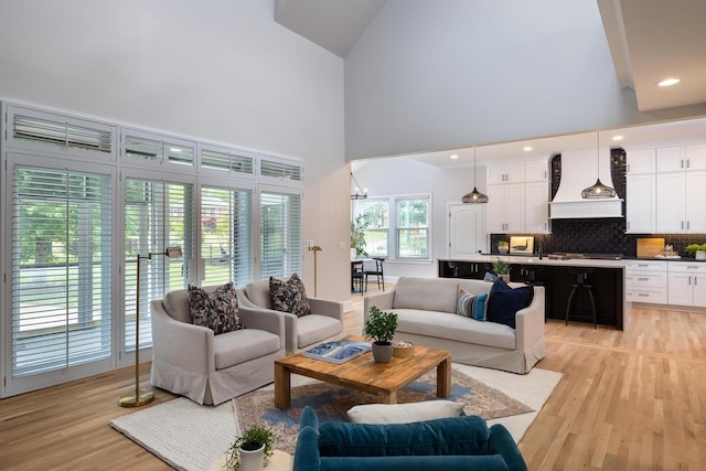 living room with light wood finished floors, a high ceiling, and recessed lighting