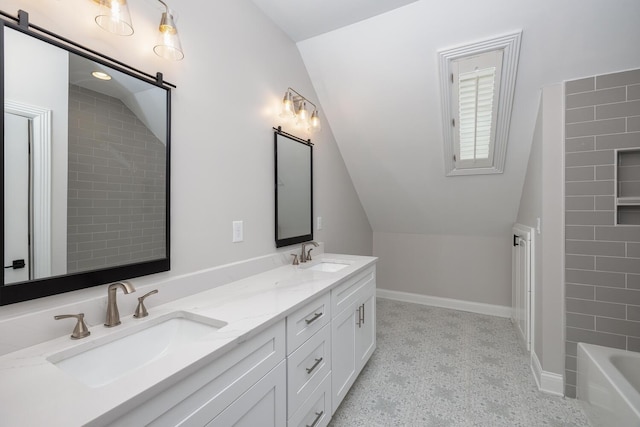 bathroom with lofted ceiling, a sink, baseboards, and double vanity