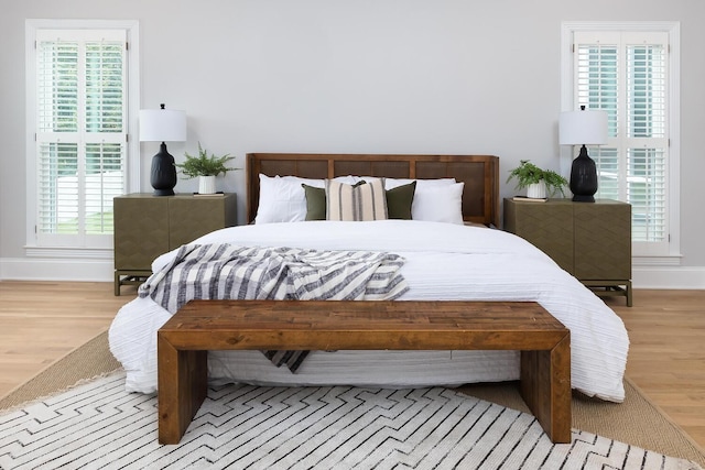 bedroom featuring light wood finished floors and baseboards