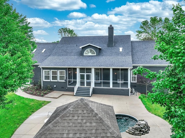 back of house with a sunroom, a shingled roof, a patio area, and a chimney