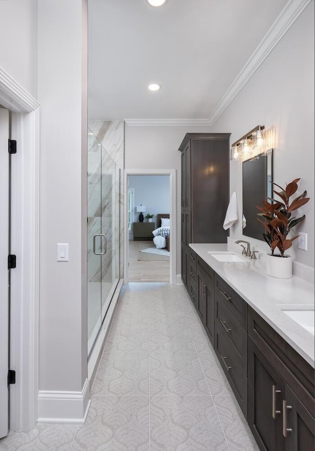 full bath with a sink, baseboards, ornamental molding, a marble finish shower, and double vanity