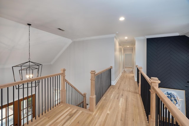 hallway featuring a chandelier, visible vents, an upstairs landing, light wood-style floors, and crown molding