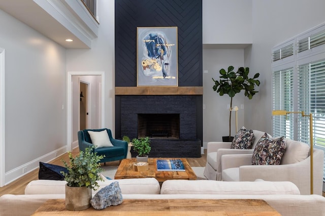 living area with baseboards, a fireplace, a high ceiling, and wood finished floors