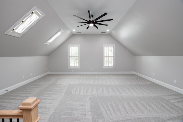 additional living space featuring light carpet, vaulted ceiling with skylight, recessed lighting, and baseboards