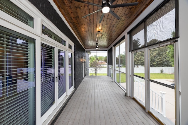 unfurnished sunroom with wood ceiling and a ceiling fan