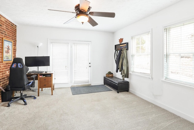 office space with a ceiling fan, light carpet, a textured ceiling, brick wall, and baseboards