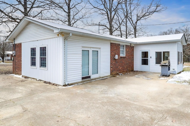 exterior space with driveway, a patio, and brick siding