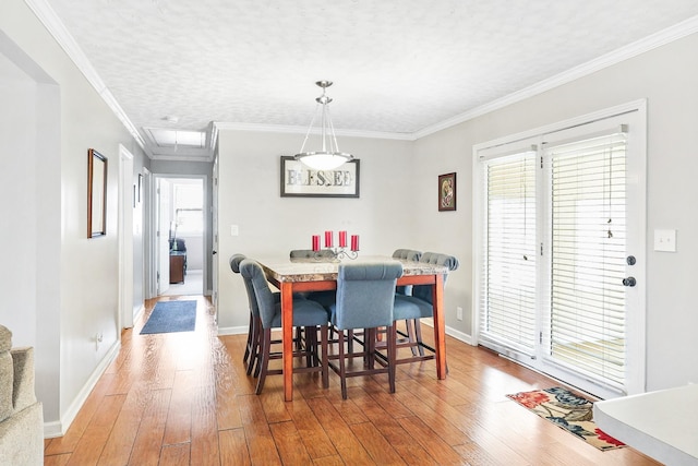 dining room with baseboards, ornamental molding, and wood finished floors