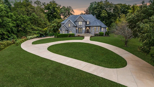 view of front of house with stone siding and a yard