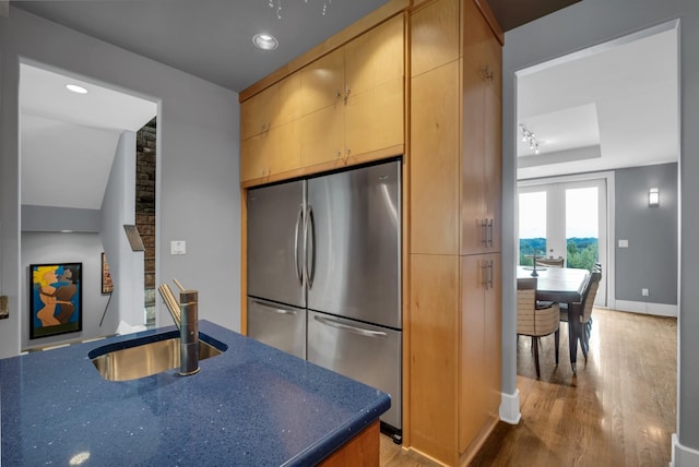 kitchen featuring light wood-type flooring, dark countertops, a sink, and freestanding refrigerator