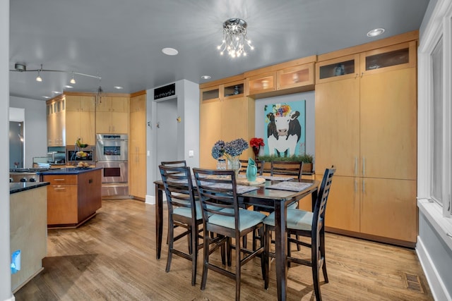 dining area with a chandelier, visible vents, and light wood finished floors