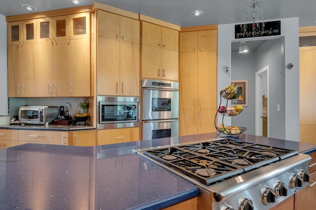 kitchen with light brown cabinets, a toaster, stainless steel appliances, tasteful backsplash, and glass insert cabinets