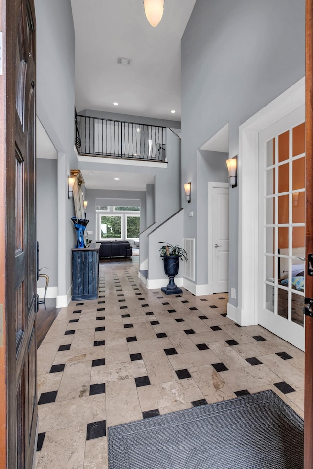 foyer with a high ceiling, visible vents, baseboards, french doors, and stairway