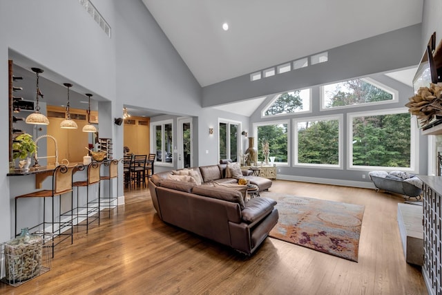 living room featuring baseboards, visible vents, high vaulted ceiling, and wood finished floors