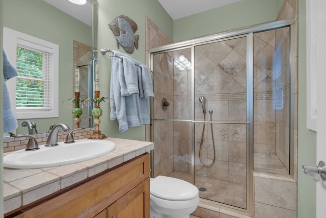 bathroom featuring toilet, a stall shower, and vanity