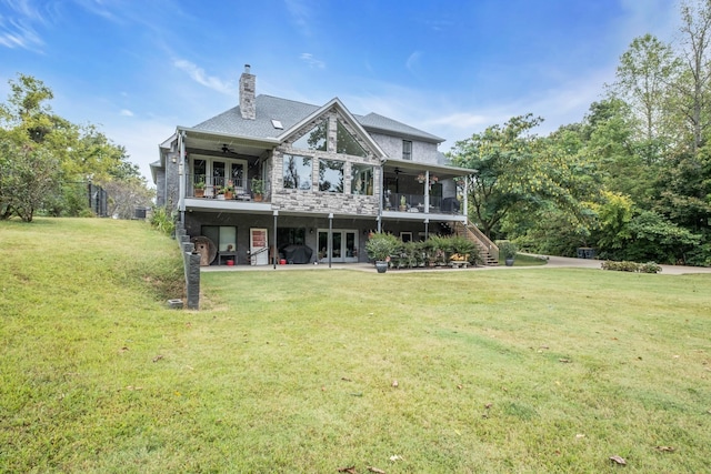 rear view of property featuring a chimney, a lawn, a patio area, ceiling fan, and stairs