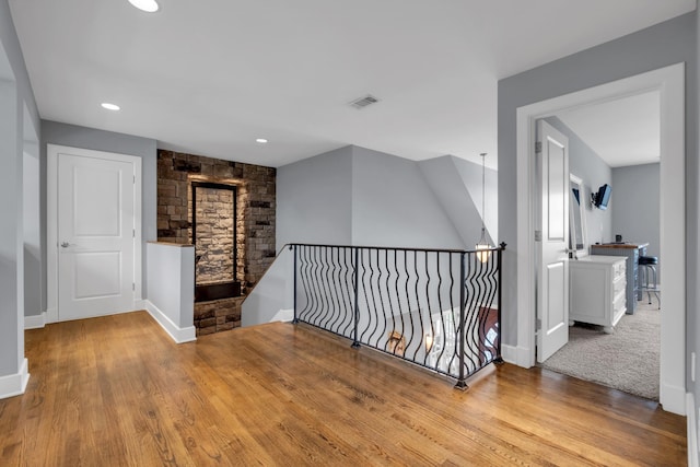 corridor with light wood finished floors, recessed lighting, visible vents, an upstairs landing, and baseboards