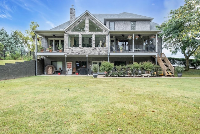 rear view of property with stone siding, ceiling fan, a chimney, stairs, and a yard