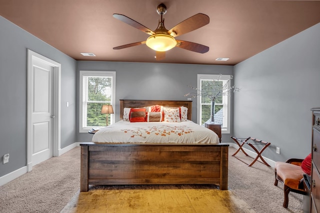 bedroom with light carpet, ceiling fan, visible vents, and baseboards