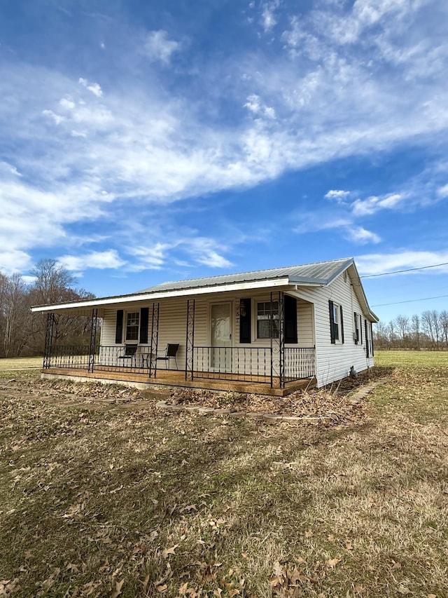 view of front facade with metal roof, a porch, and a front yard