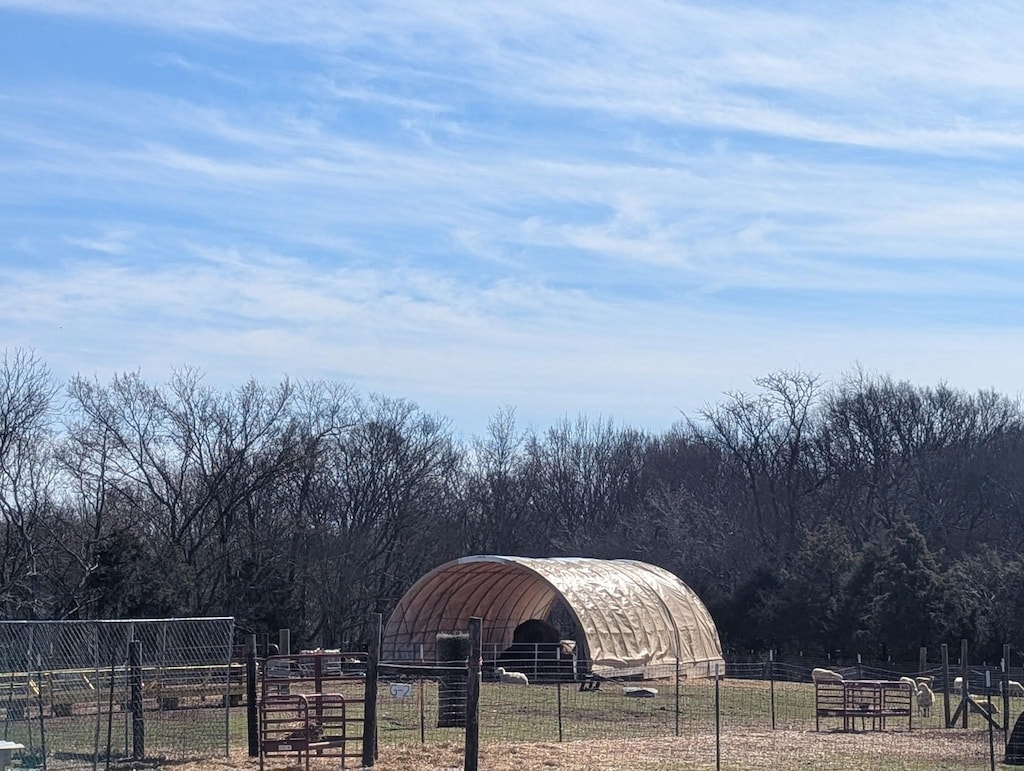 exterior space with a rural view, fence, and an outdoor structure