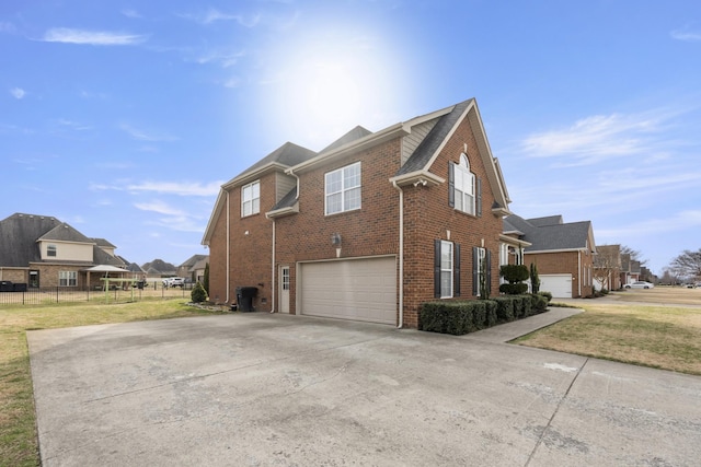 view of side of home with driveway, a garage, a lawn, fence, and brick siding