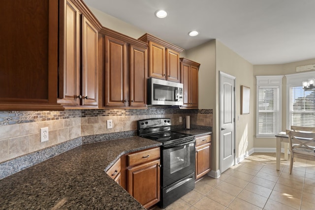 kitchen featuring dark stone countertops, brown cabinetry, stainless steel microwave, and black electric range oven