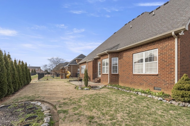 view of property exterior with a shingled roof, crawl space, fence, a yard, and brick siding