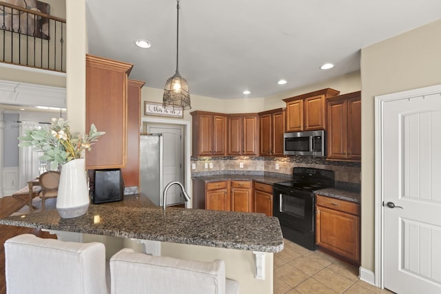 kitchen featuring black electric range oven, a sink, brown cabinets, stainless steel microwave, and a kitchen bar