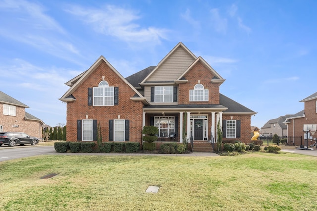 view of front of house featuring a porch, brick siding, and a front lawn